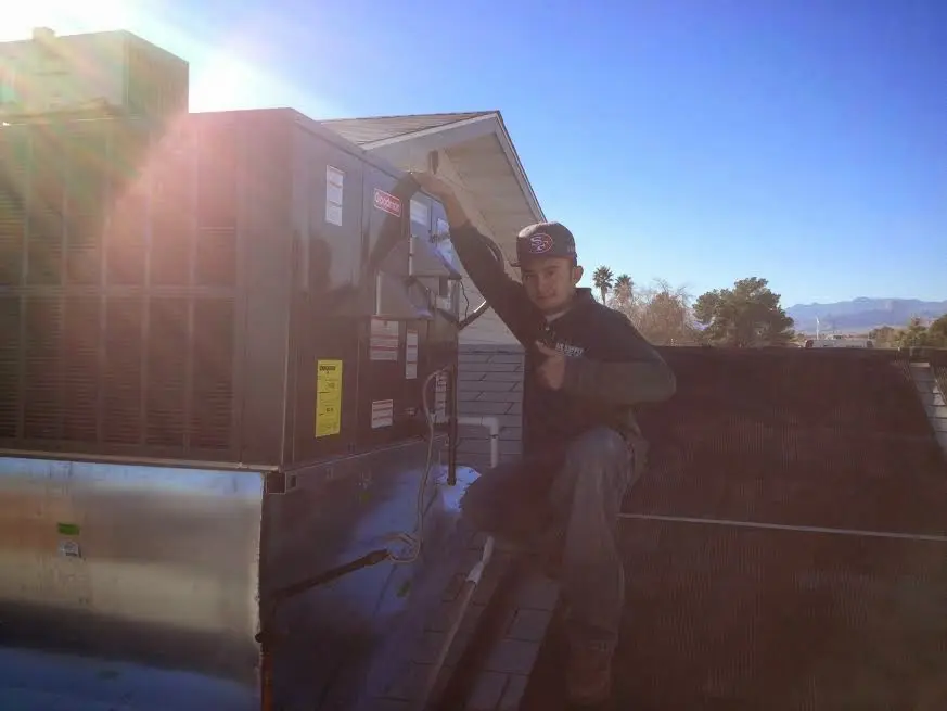 HVAC technician performing Air Duct Repair on a rooftop unit in Lawrence